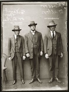 three men in suits and hats standing next to each other with their hands on their hips