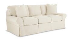 a white couch with four pillows on it's back and one arm facing the camera