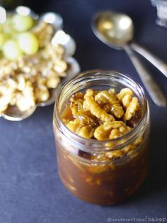 a jar filled with nuts sitting on top of a table next to a bowl of grapes