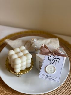 a white plate topped with marshmallows next to a small gift box on top of a table