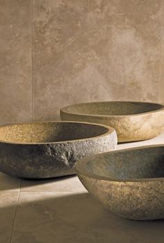 three stone bowls sitting on top of a floor next to each other in front of a wall