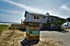 a house on the beach with a sign in front