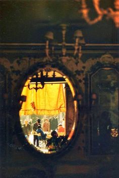 the reflection of people sitting at a table in front of a mirror on a wall