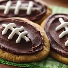 cookies decorated with chocolate frosting and footballs on a green napkin sitting on a wooden table