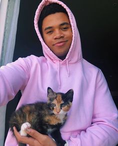 a man in a pink hoodie holding a cat