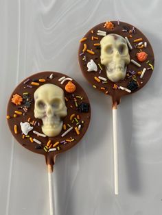 two chocolate lollipops decorated with skulls and sprinkles