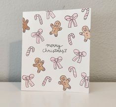 a christmas card with gingerbreads and candy canes on white paper, sitting on a table