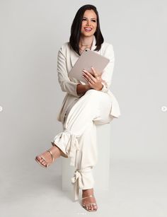 a woman sitting on top of a white chair holding a piece of paper