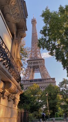 the eiffel tower in paris, france is seen from behind some buildings and trees