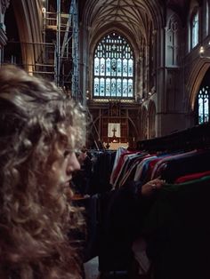 a woman standing in front of a window next to a bunch of clothes on racks