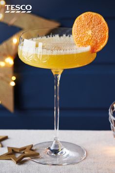 an orange slice on top of a drink in a wine glass next to star decorations