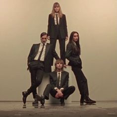 a group of people in suits and ties posing for a photo with one person sitting on the ground