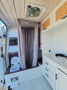 the inside of a camper with white cabinets and wood flooring on the walls