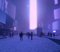 people are walking through the snow in front of tall buildings and skyscrapers at night