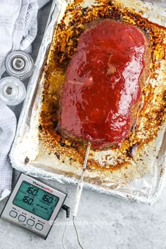 a meatloaf with ketchup on top and thermometer next to it