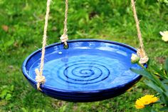 a blue bird bath hanging from a rope