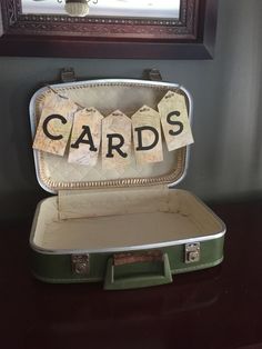 an open suitcase sitting on top of a table next to a framed mirror with cards in it