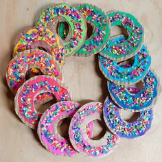 donuts with sprinkles are arranged in a circle on a table top