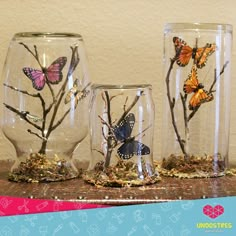 three glass vases with butterflies on them sitting on a table next to each other