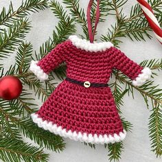 a crocheted christmas ornament hanging from a pine tree with candy canes