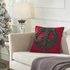 a peace sign pillow sitting on top of a white couch next to a christmas tree