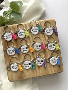 a bunch of key chains that are on a wooden board with flowers in the background