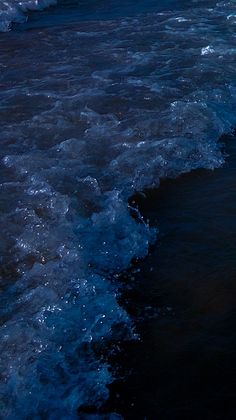 a person riding a surfboard on top of a wave in the ocean at night