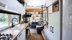 the interior of a tiny home with white cabinets and wood flooring, along with an open kitchen area