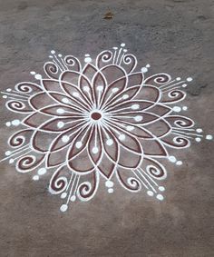 an intricate design on the ground with white dots and circles around it, painted in brown and white