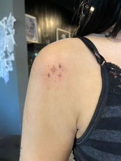 the back of a woman's shoulder with a small star tattoo on her left arm