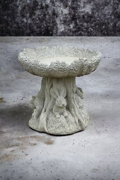 a white ceramic bird bath sitting on top of a cement floor