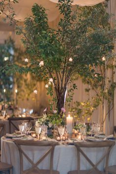 the table is set with candles, flowers and greenery for an elegant wedding reception