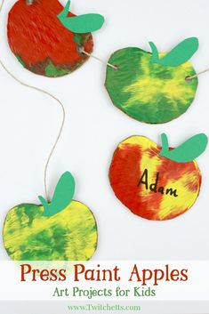 paper apples with the words press paint apples on them and some green leaves hanging from strings