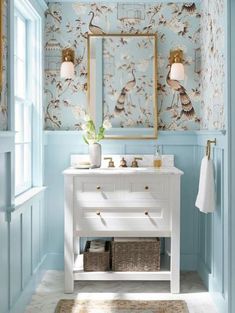 a bathroom with blue walls and a white vanity topped with a mirror next to a window