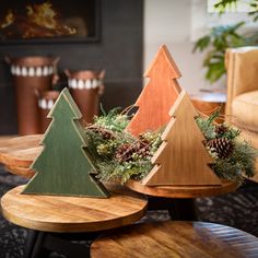 three wooden christmas trees sitting on top of small tables in front of a fire place