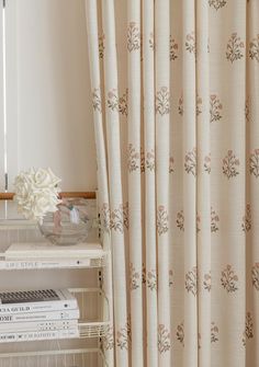 there is a vase with flowers on top of a shelf next to a window curtain