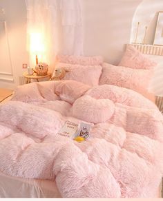 a bed with pink fluffy comforters and pillows