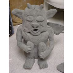 a clay sculpture of a cat with its eyes closed and mouth wide open, sitting on the ground