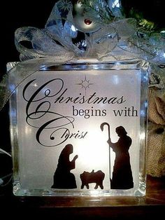 a lighted glass block with the words christmas begins with jesus