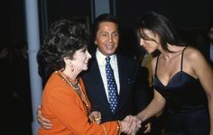 two women shaking hands with a man in a suit