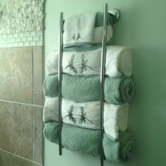 towels are stacked up on the wall next to a towel rack in a green bathroom