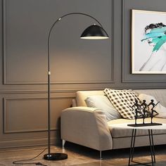 a living room with a couch, table lamp and pictures on the wall behind it