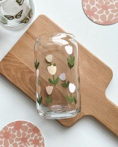 a wooden cutting board topped with glasses filled with water and hearts cut out of paper