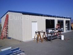 a small metal building with a ladder next to it and tools on the table outside