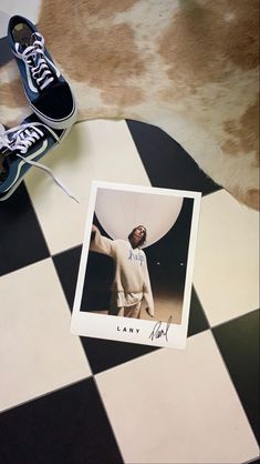 a pair of tennis shoes sitting on top of a black and white checkered floor