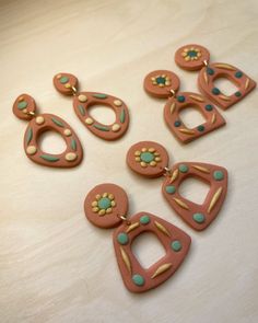 five pieces of clay sitting on top of a wooden table next to each other with holes in the middle