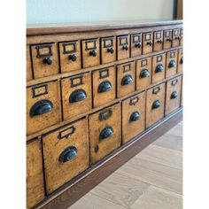 an old wooden filing cabinet with many drawers and knobs on the front, sitting on a hard wood floor