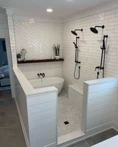 a bathroom with white tiles and black fixtures on the walls, along with a large walk in shower