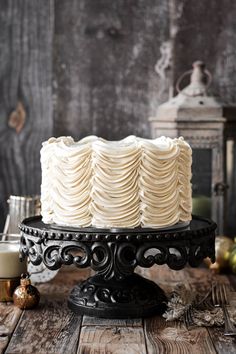 a white frosted cake sitting on top of a wooden table