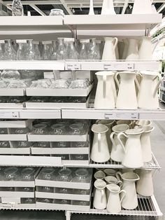 the shelves are filled with white vases and other items in plastic bins for sale